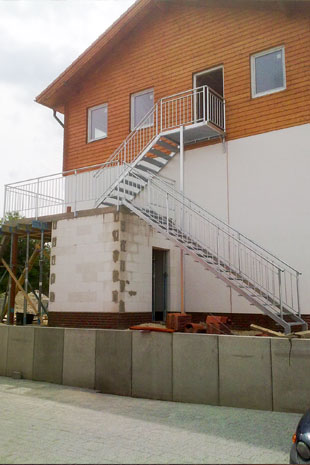 Außentreppe zu einem gemauerten Podest in feuerverzinktem Stahl inklusive Galeriegeländern auf dem Podest und Steigungsgeländern auf den Treppen