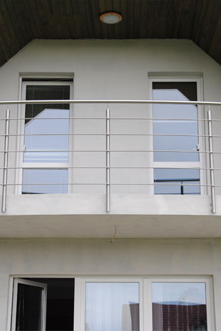 Balkongeländer mit parallelen Streben an den Pfosten geschweißt, von der Stirnseite des Gebäudes montiert, Handlauf und Pfosten 42mm, Füllung fi12 Vollrundmaterial