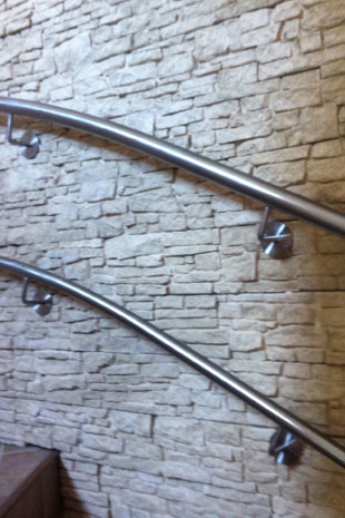 Formschöne Handläufe gebogen zum Treppenverlauf in Rundrohr Edelstahl 42mm, montiert auf Edelstahl Handlaufhaltern wandseitig, voll verschweißt